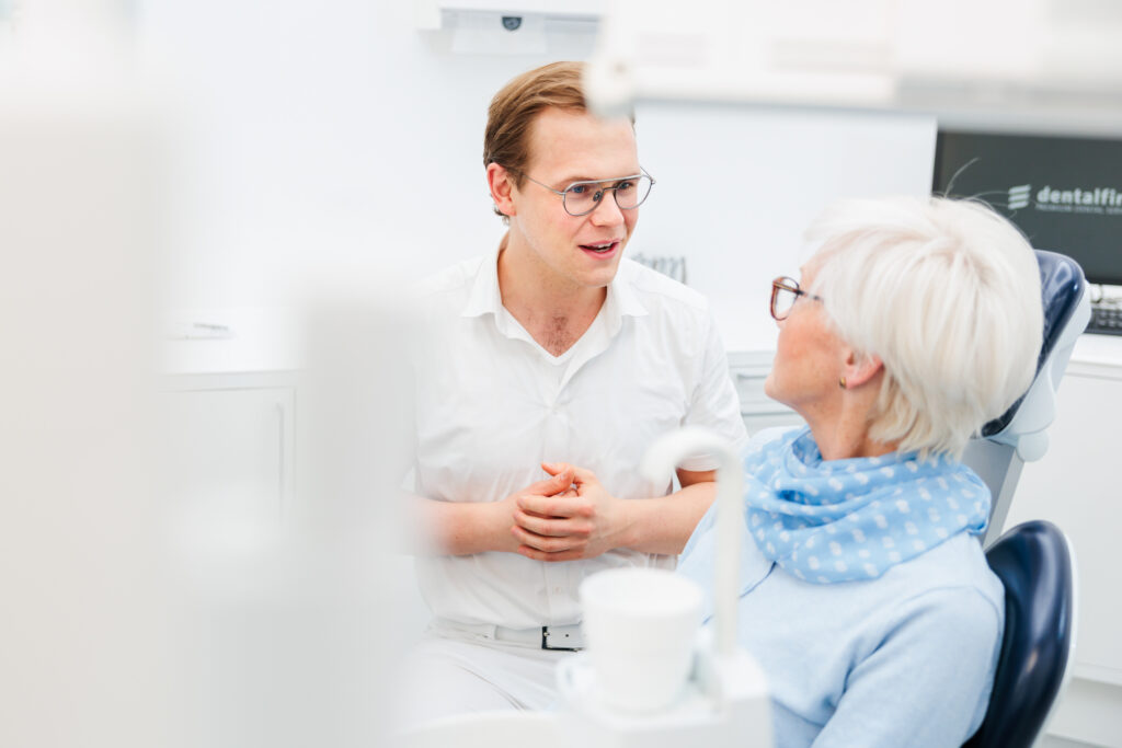 Zahnarzt Dr. Nowak erklärt einer Patientin in Berlin Zahnersatz ohne Implantate verständlich.