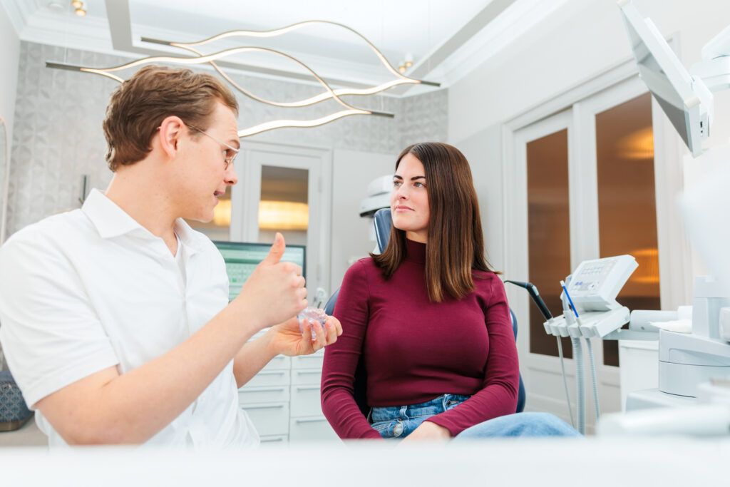 Zahnarzt Dr. Nowak erklärt einer Patientin in Berlin, wie ein gereizter Zahnnerv beruhigt werden kann.